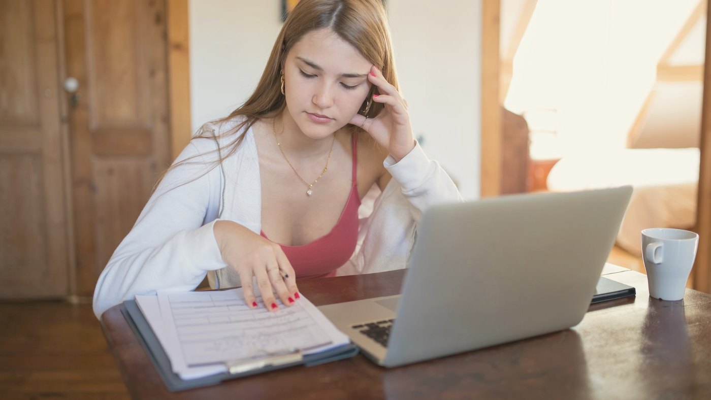 Young woman focused on documents and a laptop at home