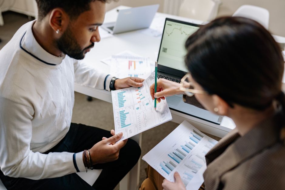 Two professionals reviewing data and graphs in a modern office