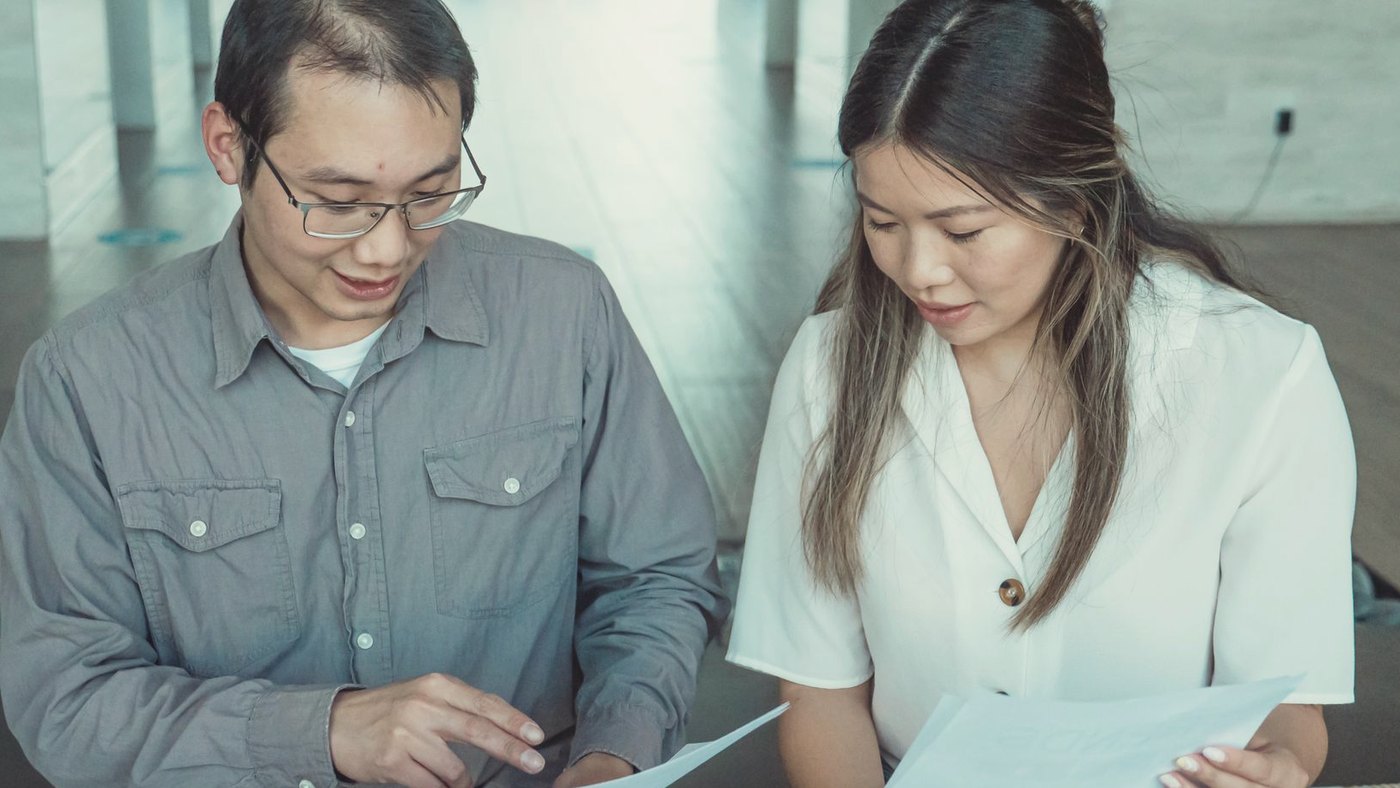 Two coworkers reviewing printed documents together at a desk