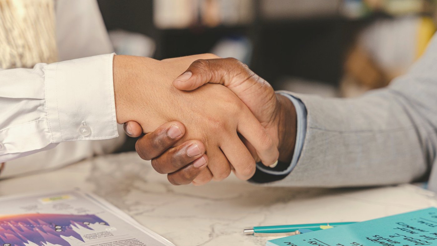 Business handshake over an office desk with documents