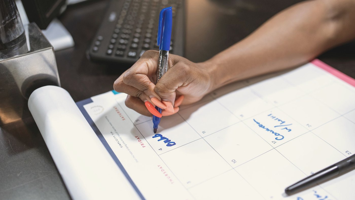 Hand writing notes on a calendar using a marker
