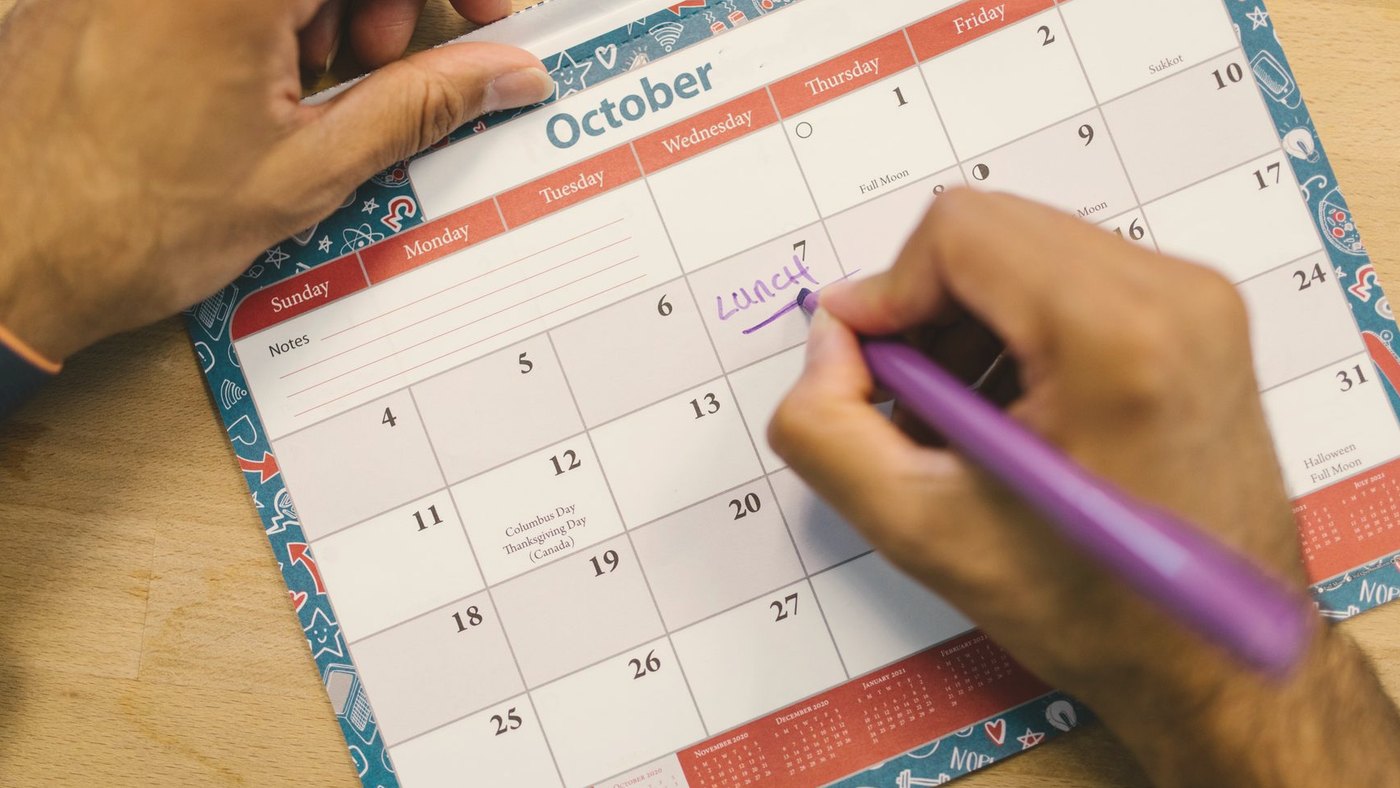 Close-up of a person writing a reminder on a calendar