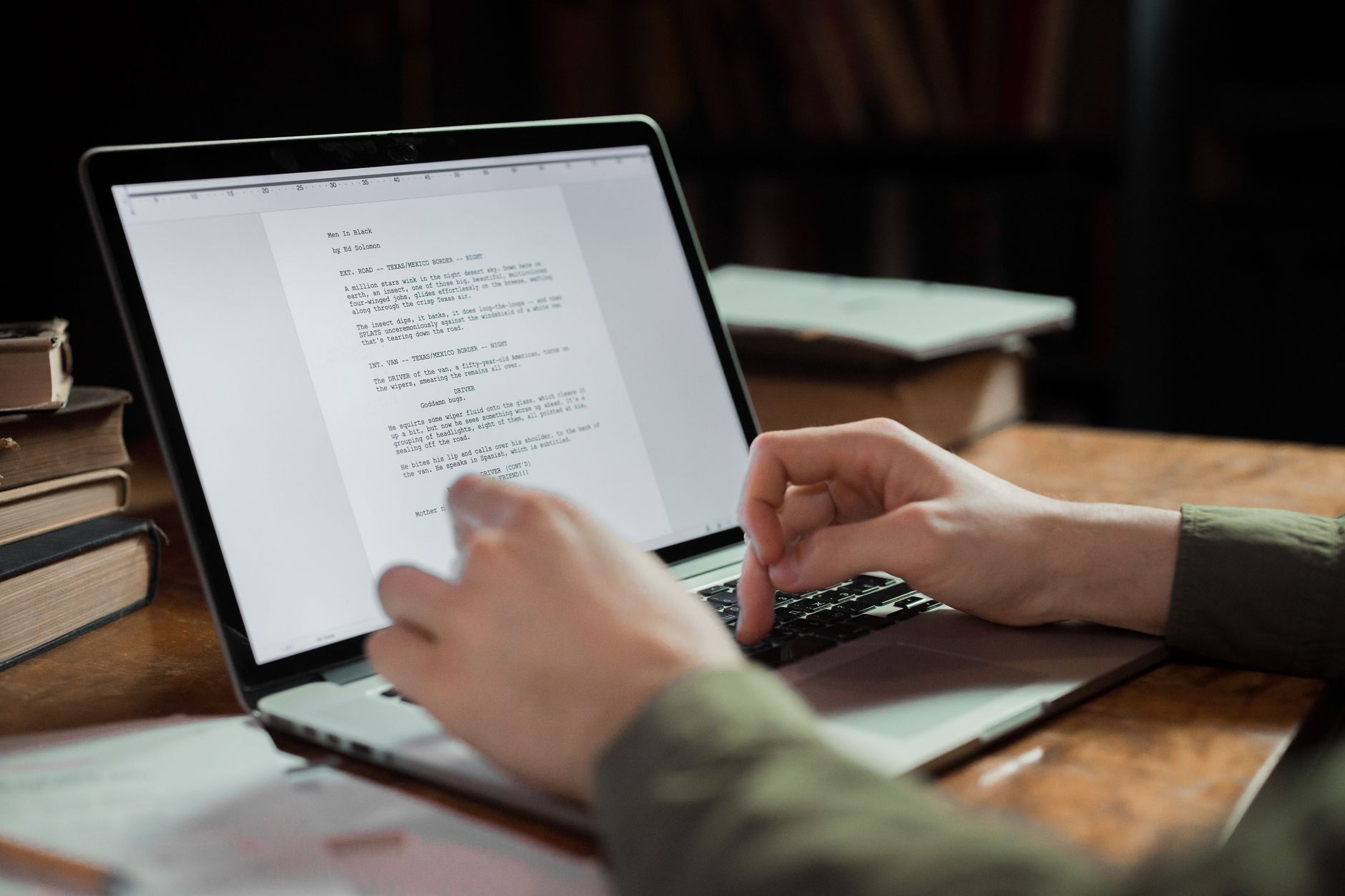 A person reviews a content draft on a laptop beside old books