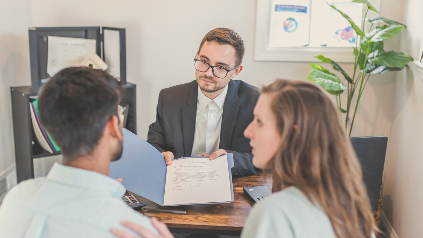 Agent and clients discussing a contract indoors