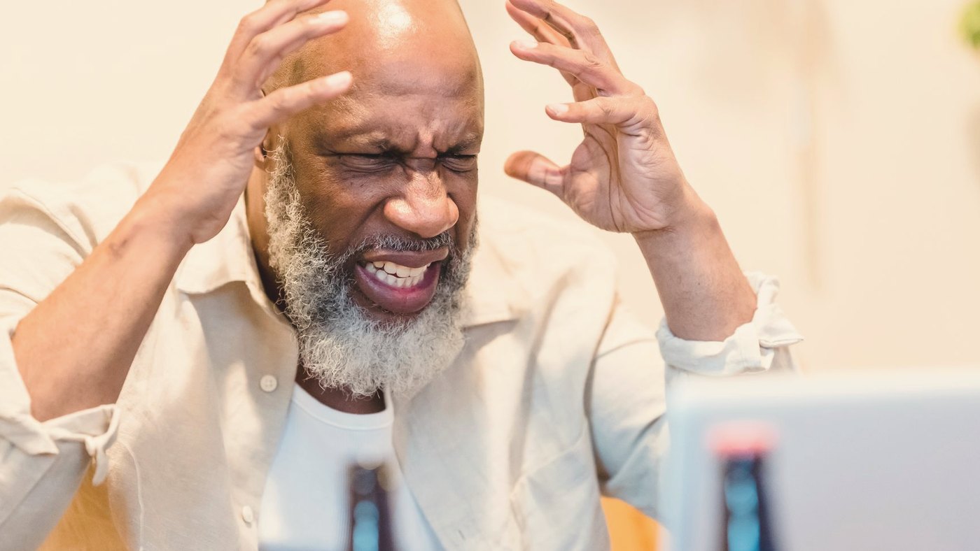 Man expressing frustration while sitting in front of a laptop
