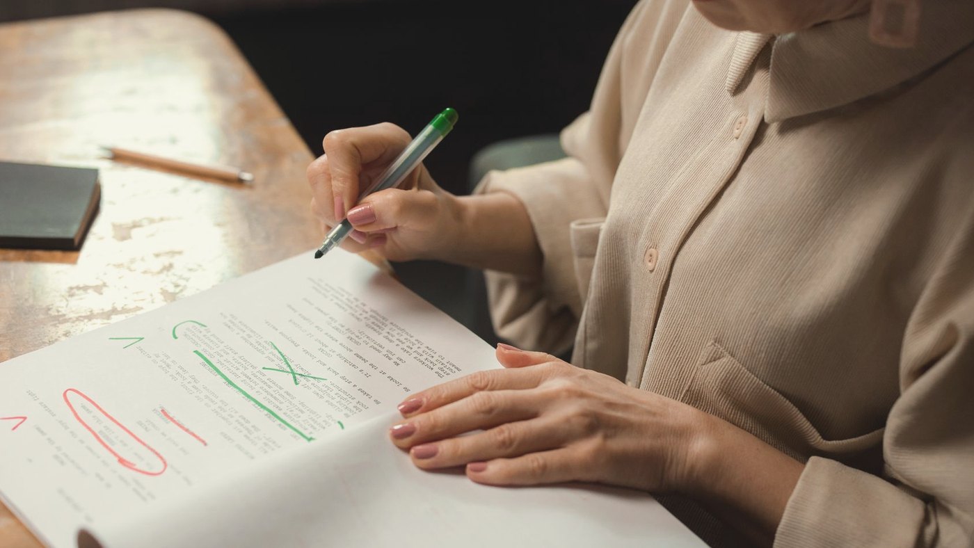 Senior woman editing a manuscript with a green marker