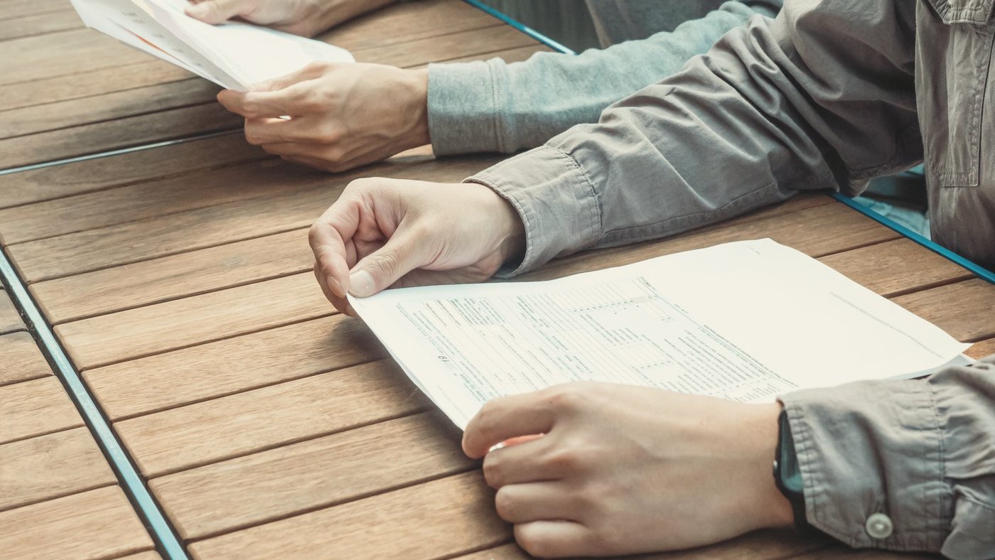 Two colleagues at an outdoor table review business papers