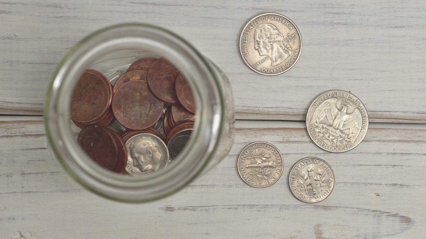 Glass jar filled with coins on a wooden table